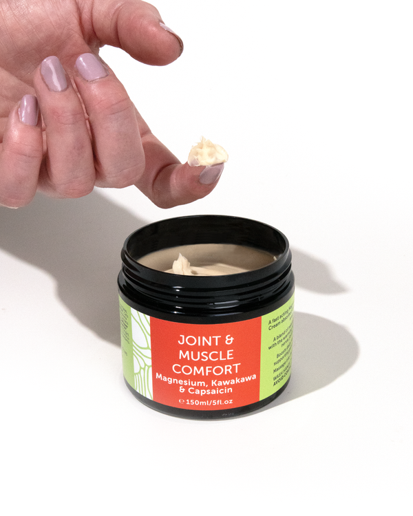 A hand scooping out some product from a tub of  Wild Kiwihearts Magnesium, Kawakawa & Capsaicin cream.